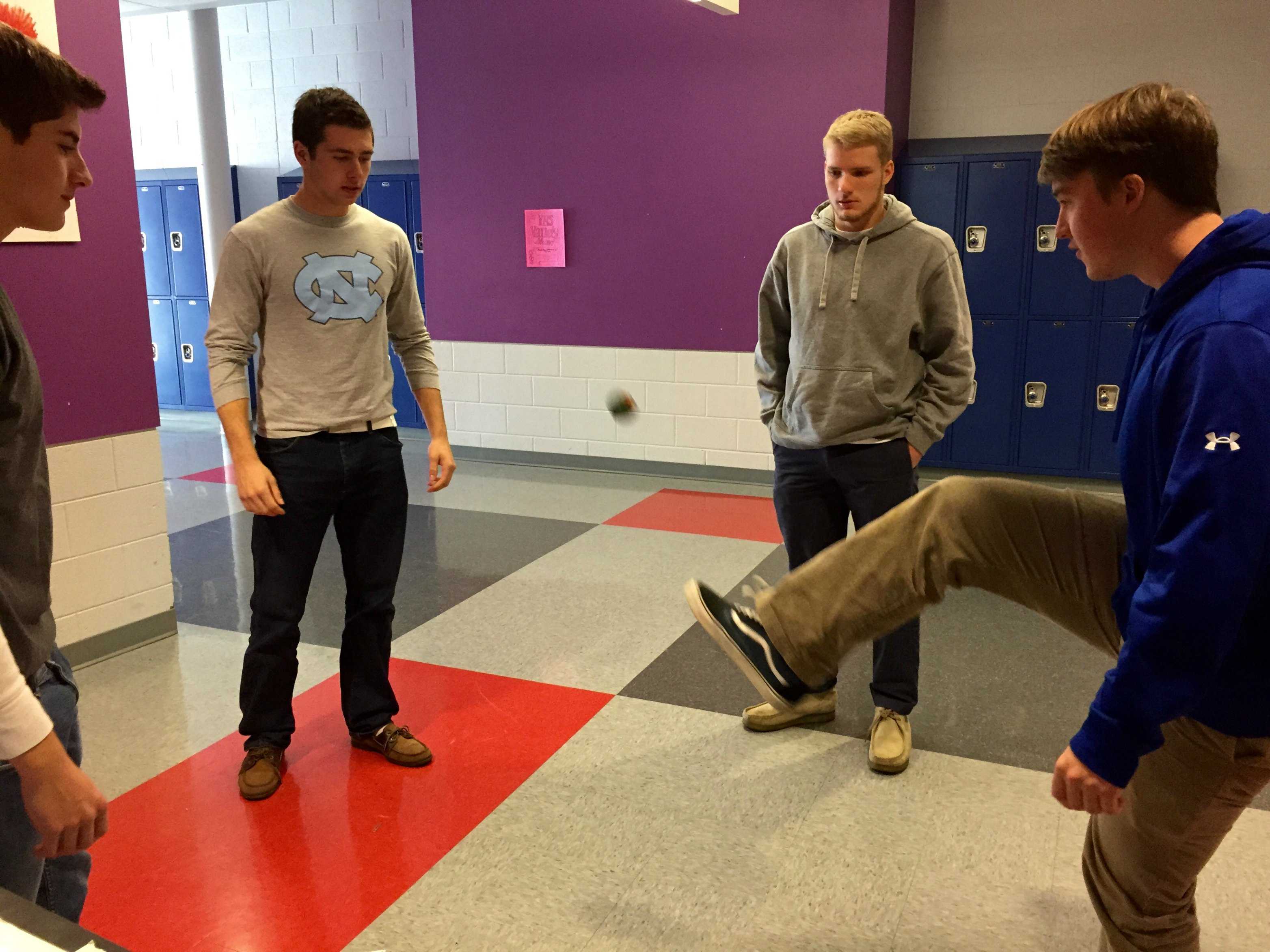 Four students hacky sack in the hallway at lunch.