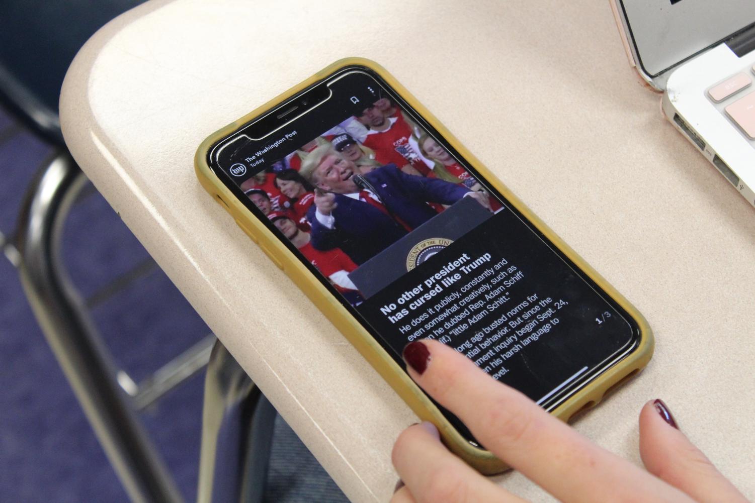 A student uses their phone to read The Washington Post.